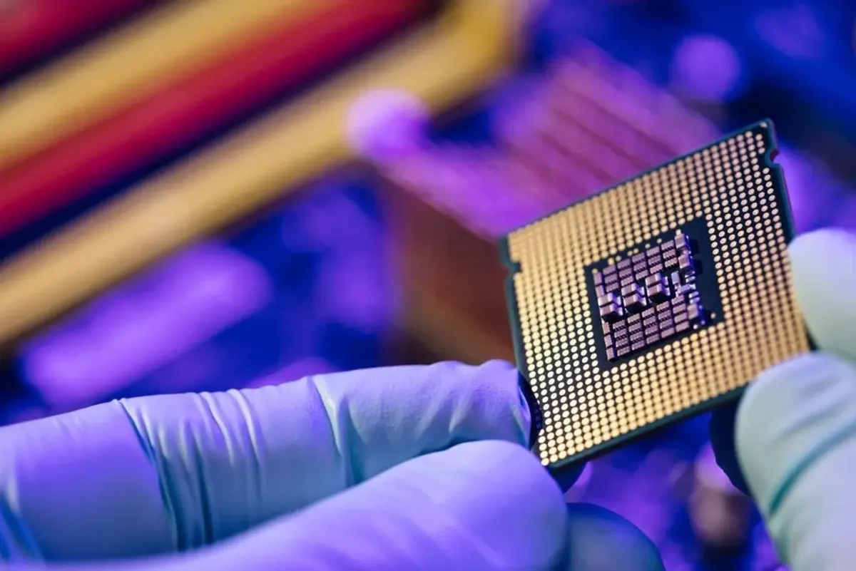 Una persona con guantes de laboratorio sostiene un chip semiconductor durante su fabricación