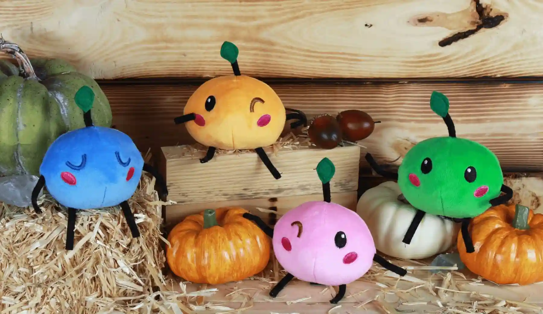 Junimos de Stardew Valley representados como peluches junto a calabazas de otoño, los espíritus del Centro Comunitario