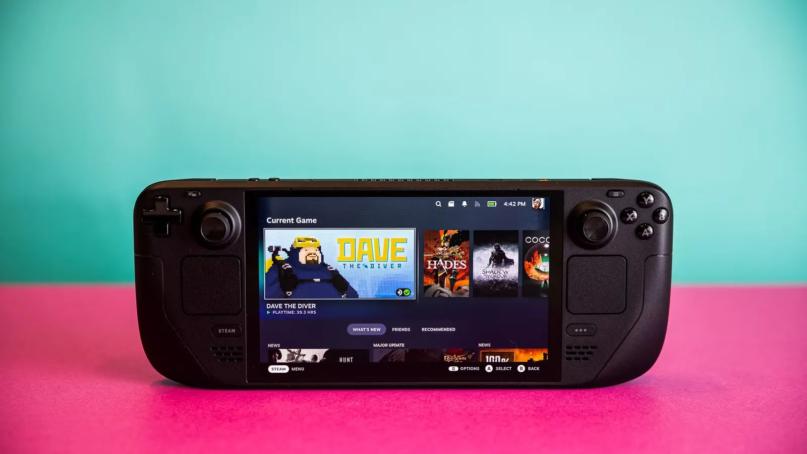 Steam Deck sobre fondo de colores mostrando su pantalla con juegos, la portátil de Valve compatible con la app