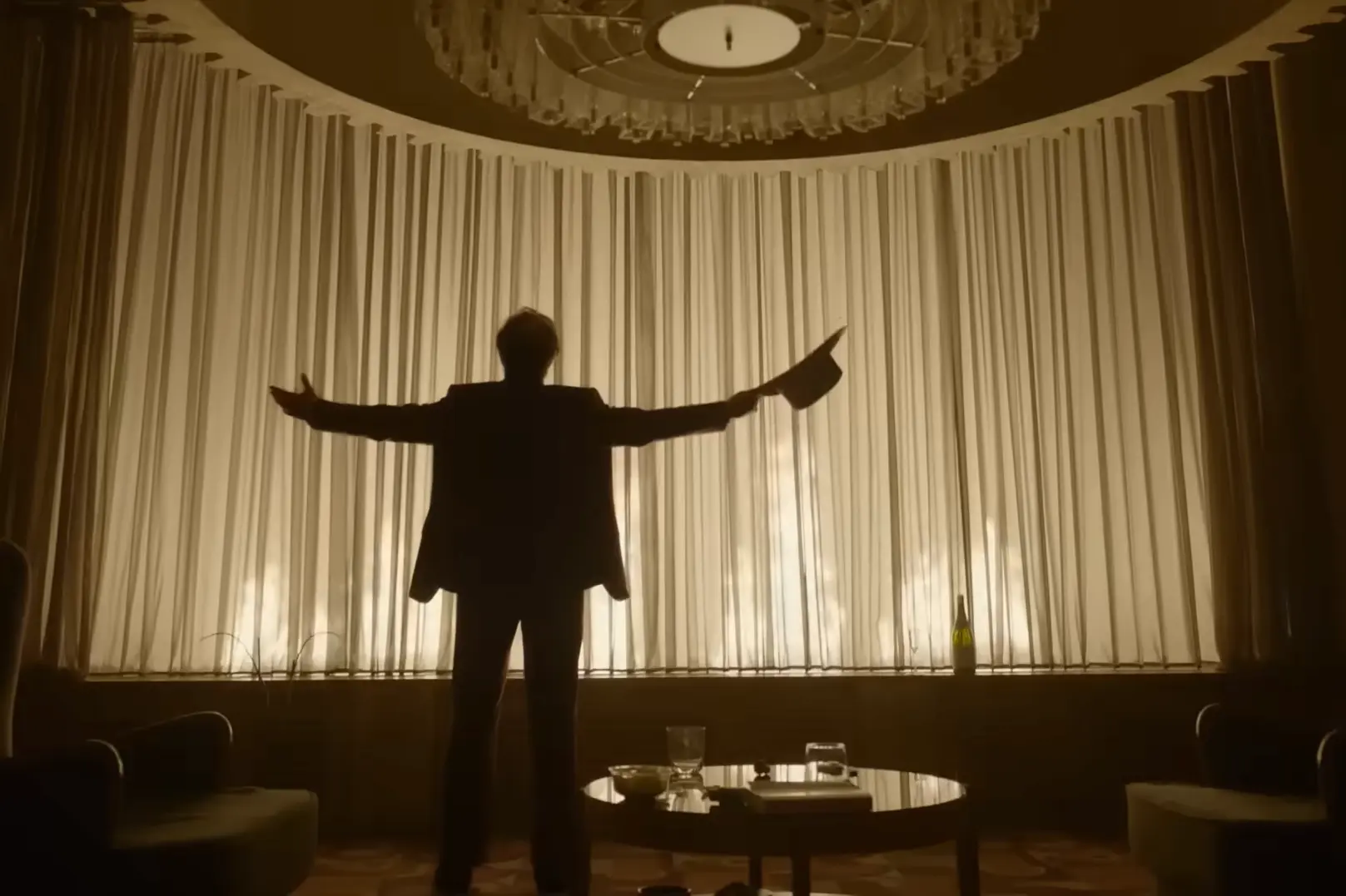 Silueta de Tom Cruise con los brazos abiertos frente a un ventanal iluminado en una escena de Digger