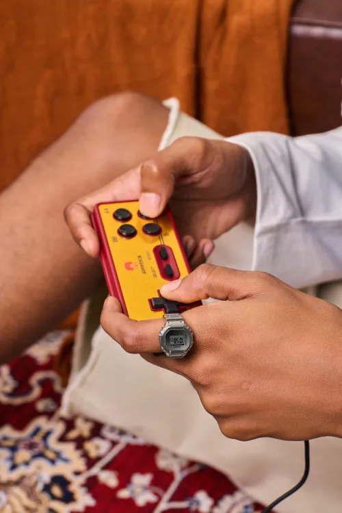 Persona con el Casio CRW-H001M-8 puesto mientras sostiene una consola portátil