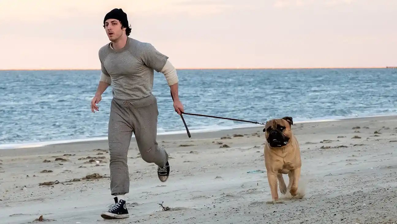 Anthony Ippolito como Stallone corre por la playa con un perro en I Play Rocky