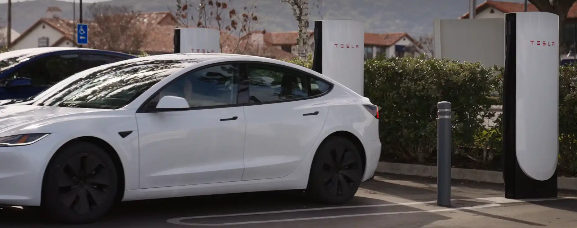 Un Tesla Model 3 blanco cargando en una estación de la marca