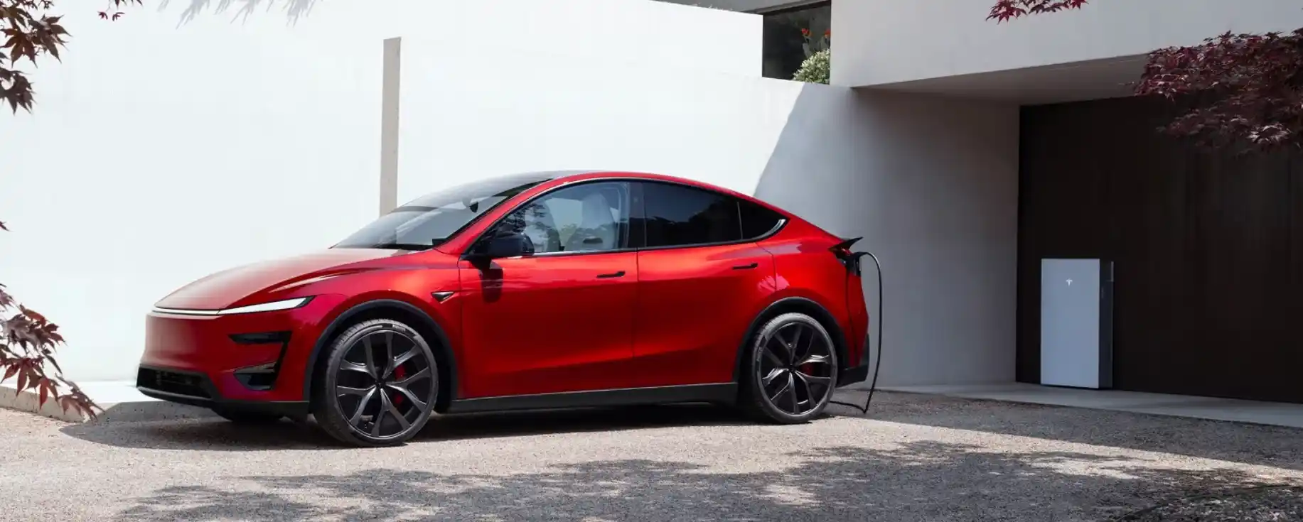 Un Tesla Model Y rojo conectado a un cargador domiciliario