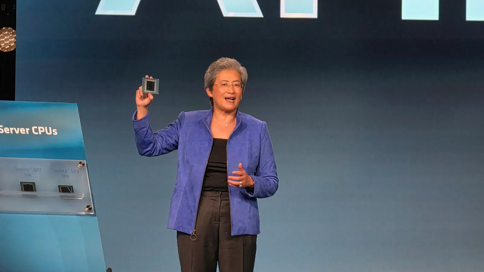 Lisa Su sostiene la CPU AMD EPYC Venice en el escenario del AMD Advancing AI 2026, junto al panel con las variantes SP7 y SP8