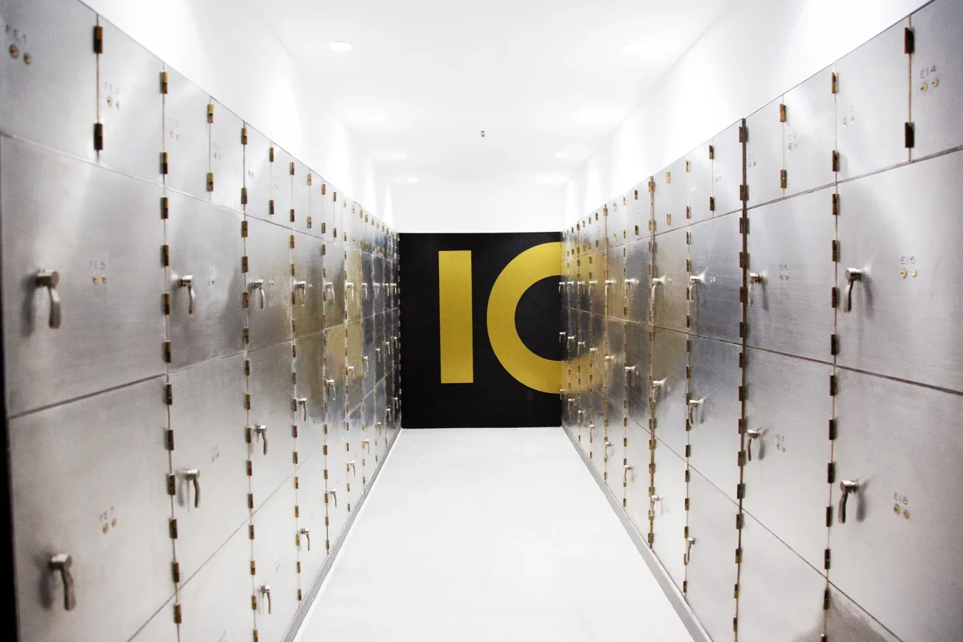Pasillo interno de la bóveda de INGOT con cajas de seguridad metálicas a ambos lados y el logo de la empresa al fondo