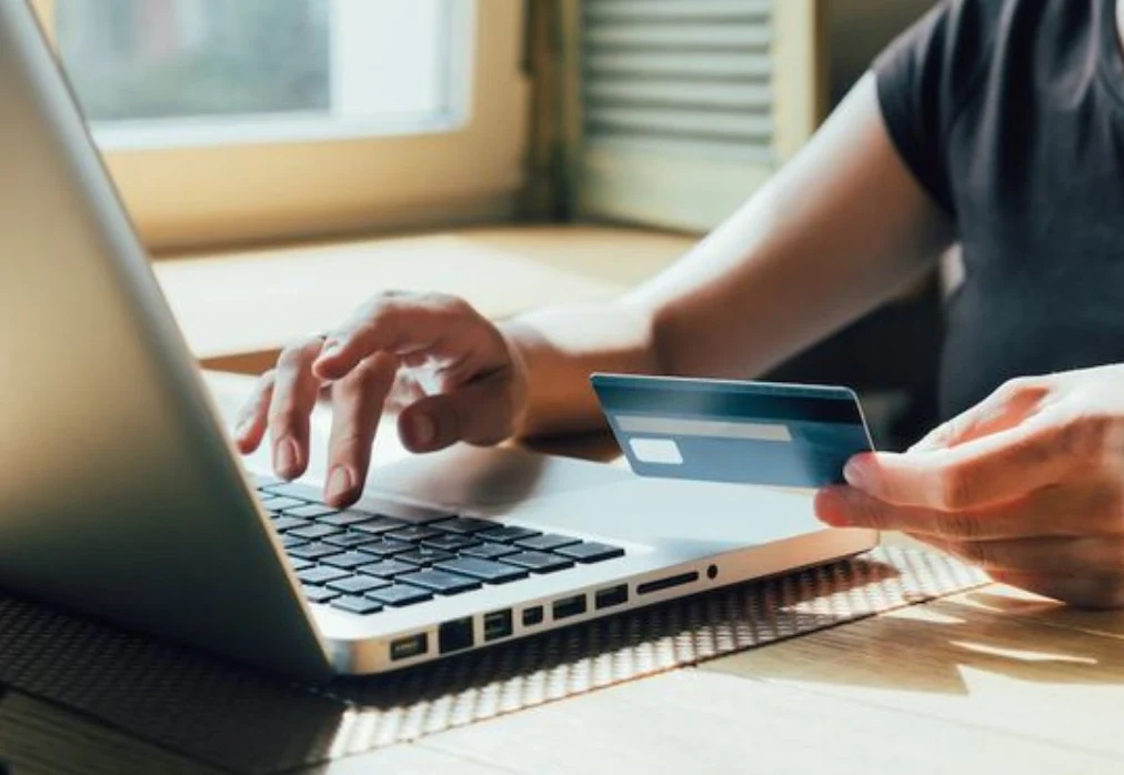 Persona pagando una compra online con tarjeta de crédito desde su notebook