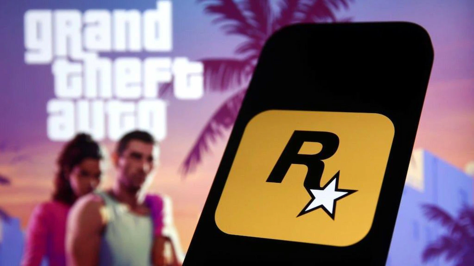 Logo de Rockstar Games en un celular frente al arte de GTA 6, el juego que sufrió la filtración del hacker