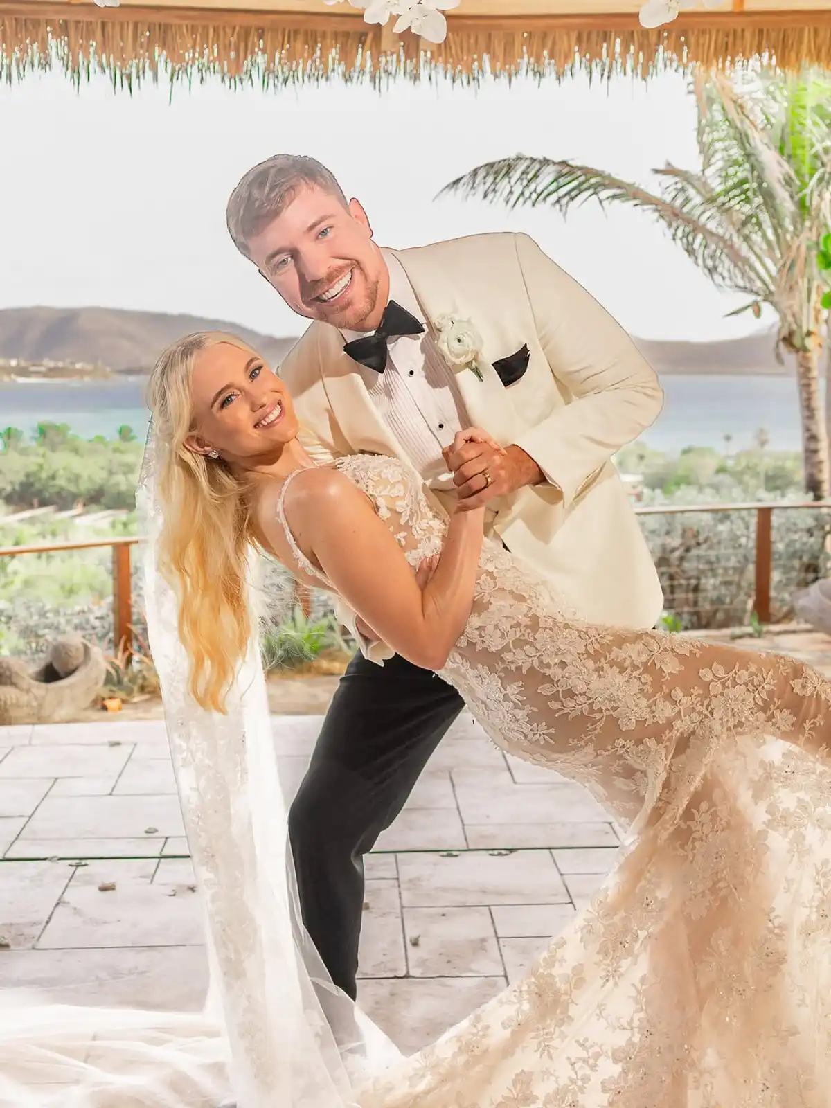 MrBeast sostiene a Thea Booysen en un paso de baile durante la fiesta de casamiento, con el mar del Caribe de fondo