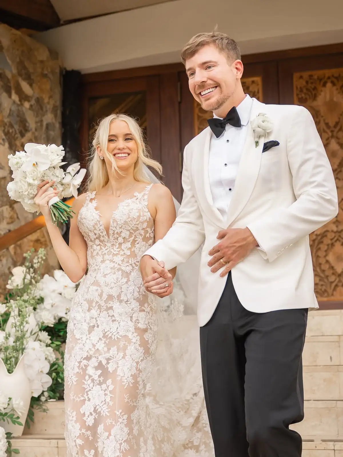 Thea Booysen sostiene el ramo de novia junto a MrBeast, de smoking blanco, el día del casamiento