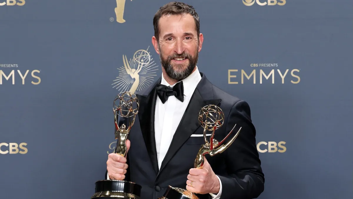 Ganador posando con dos estatuillas Emmy en la alfombra roja de una ceremonia anterior