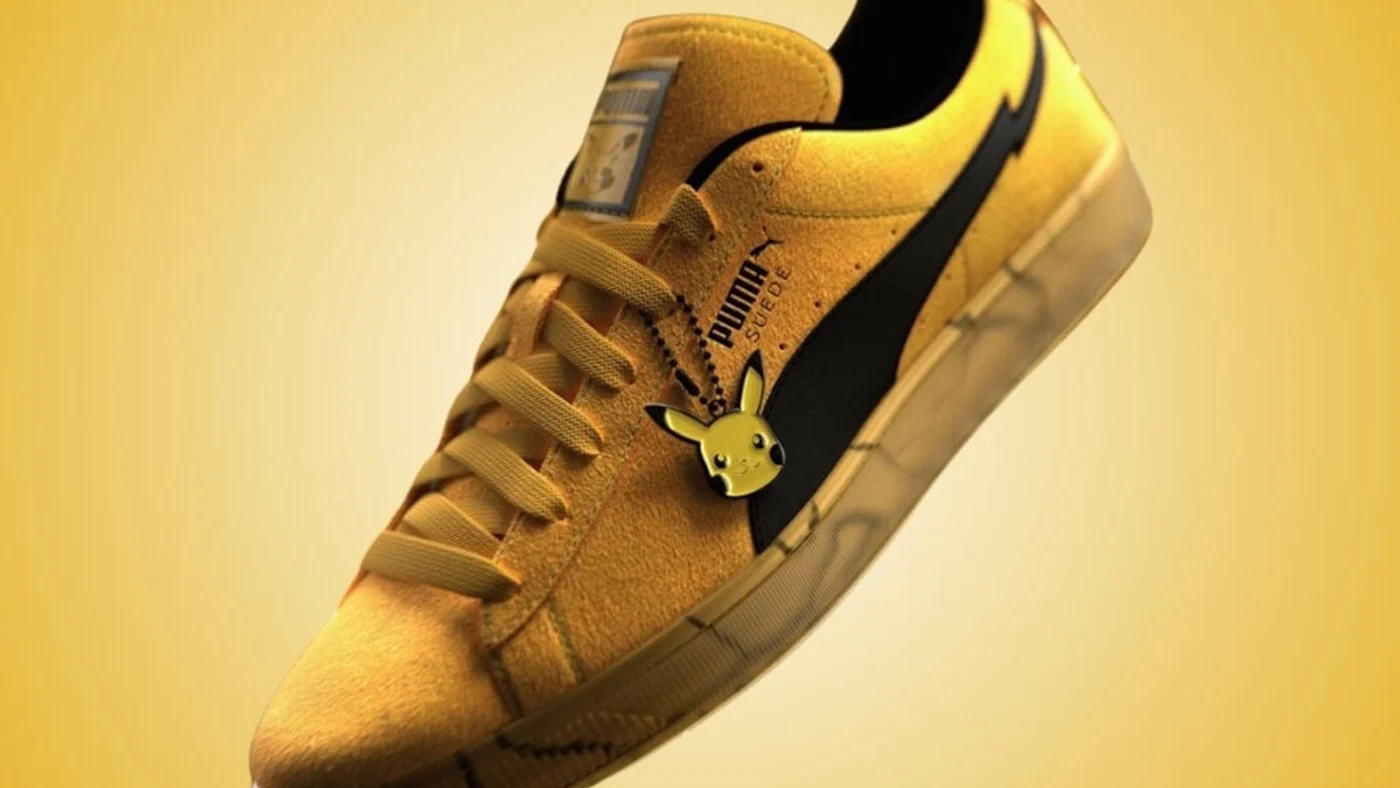 Detalle de las PUMA x Pokémon Suede Pikachu: gamuza amarilla, Formstrip negro con forma de rayo y dije de Pikachu en los cordones