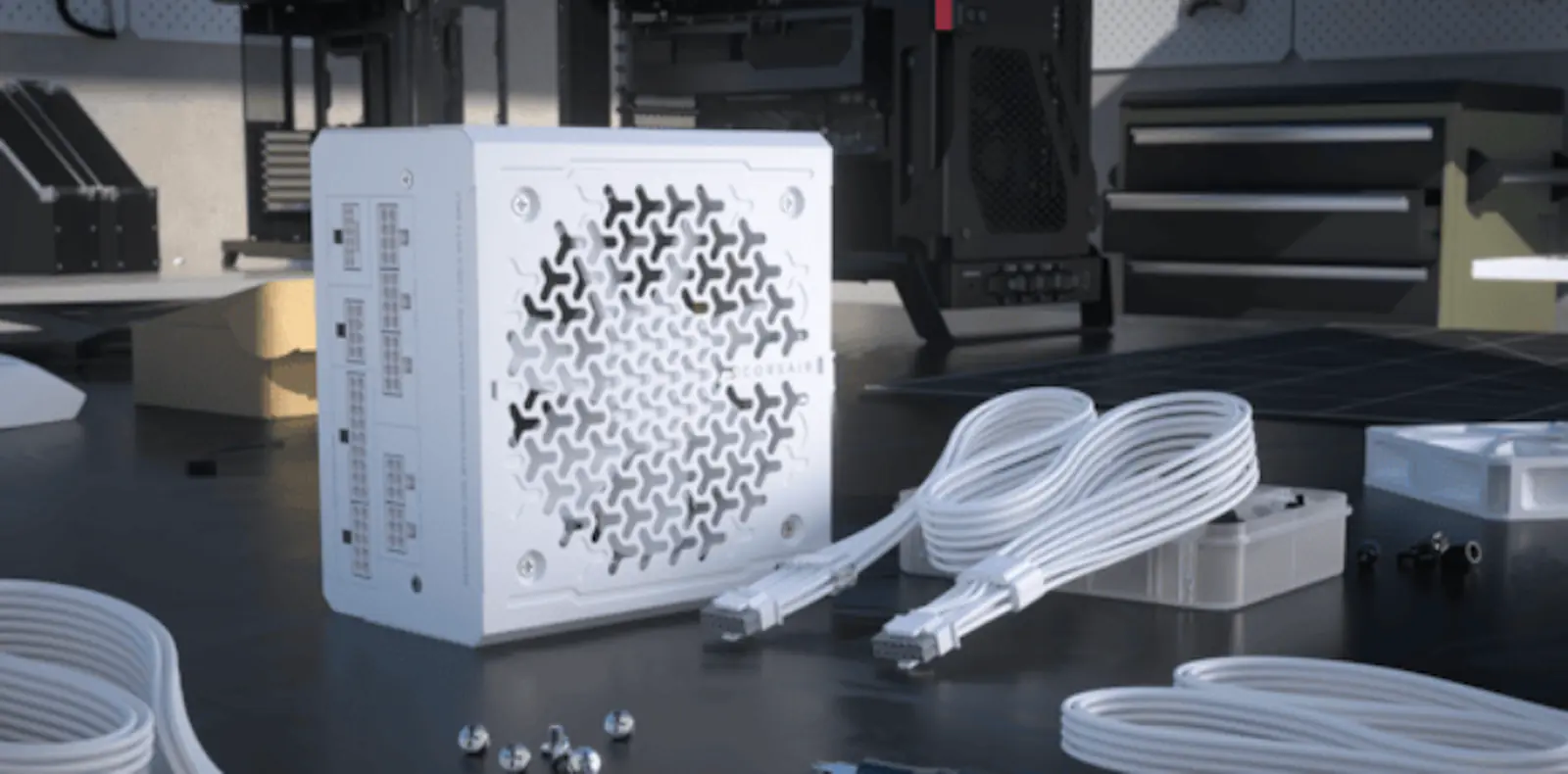 Fuente Corsair RMe blanca apoyada en un banco de trabajo junto a sus cables modulares blancos