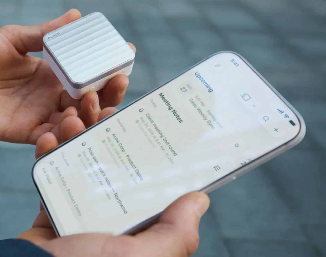 Una persona sostiene el estuche de los Plaud One junto a un celular con las notas de la reunión
