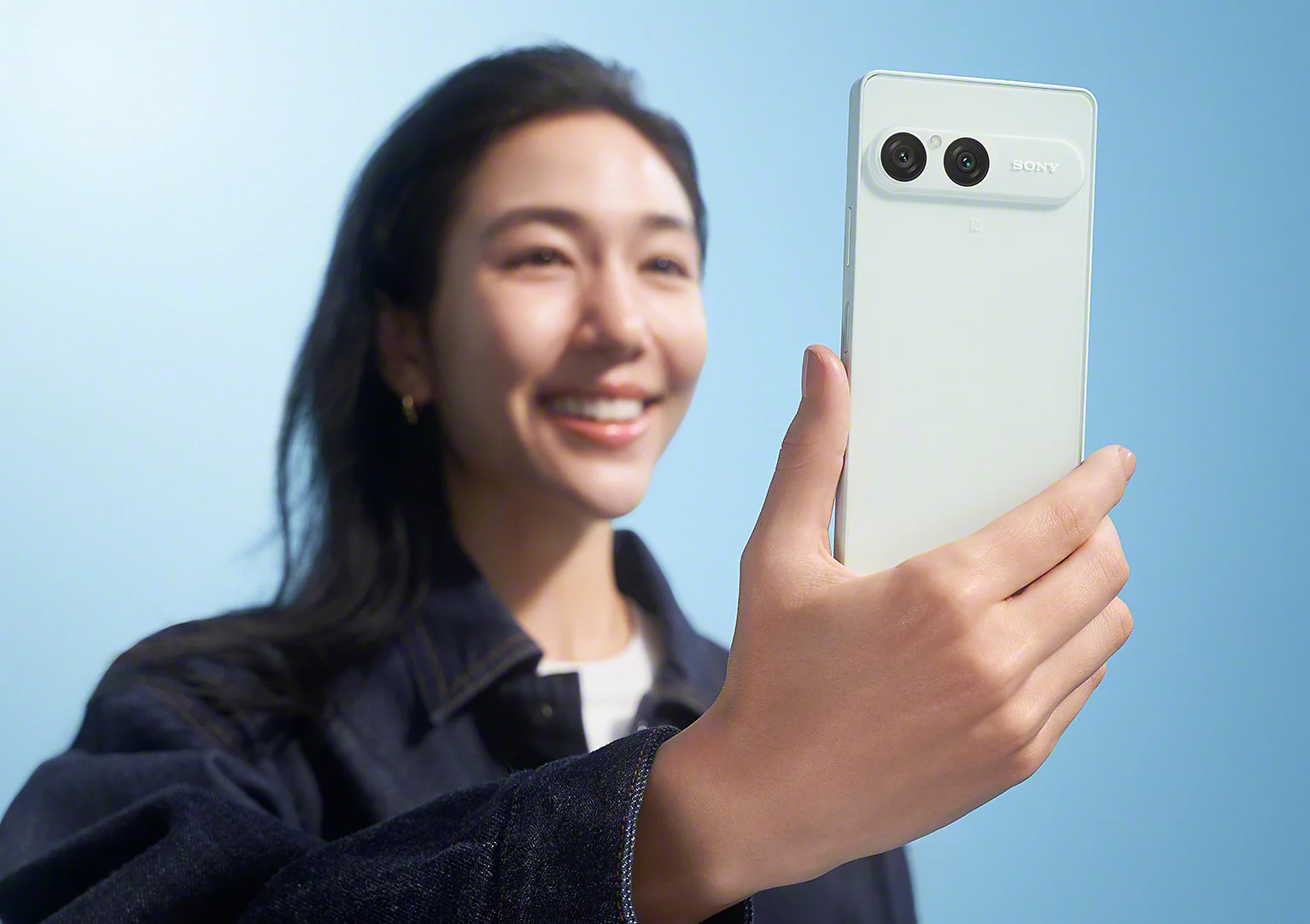 Una mujer sostiene el Sony Xperia 10 VIII en color Frozen White y muestra su cámara doble trasera