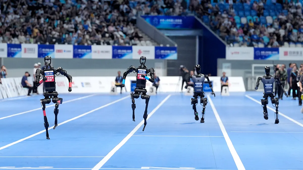 Cuatro robots humanoides corriendo por una pista de atletismo azul durante los World Humanoid Robot Games en Beijing