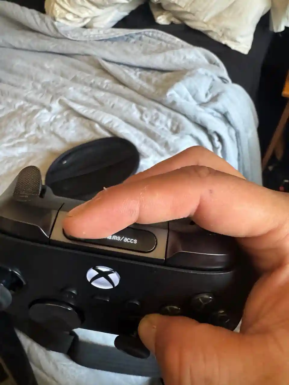 Primer plano de la pantalla encendida del supuesto Xbox Elite Series 3, con una dirección web que el dedo del usuario tapa en parte