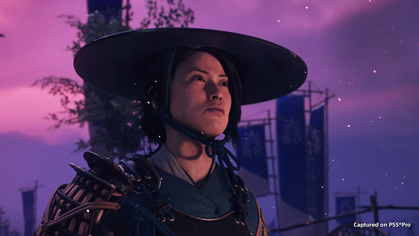 Atsu, protagonista de Ghost of Yotei Complete Edition, con su sombrero de paja y armadura al atardecer