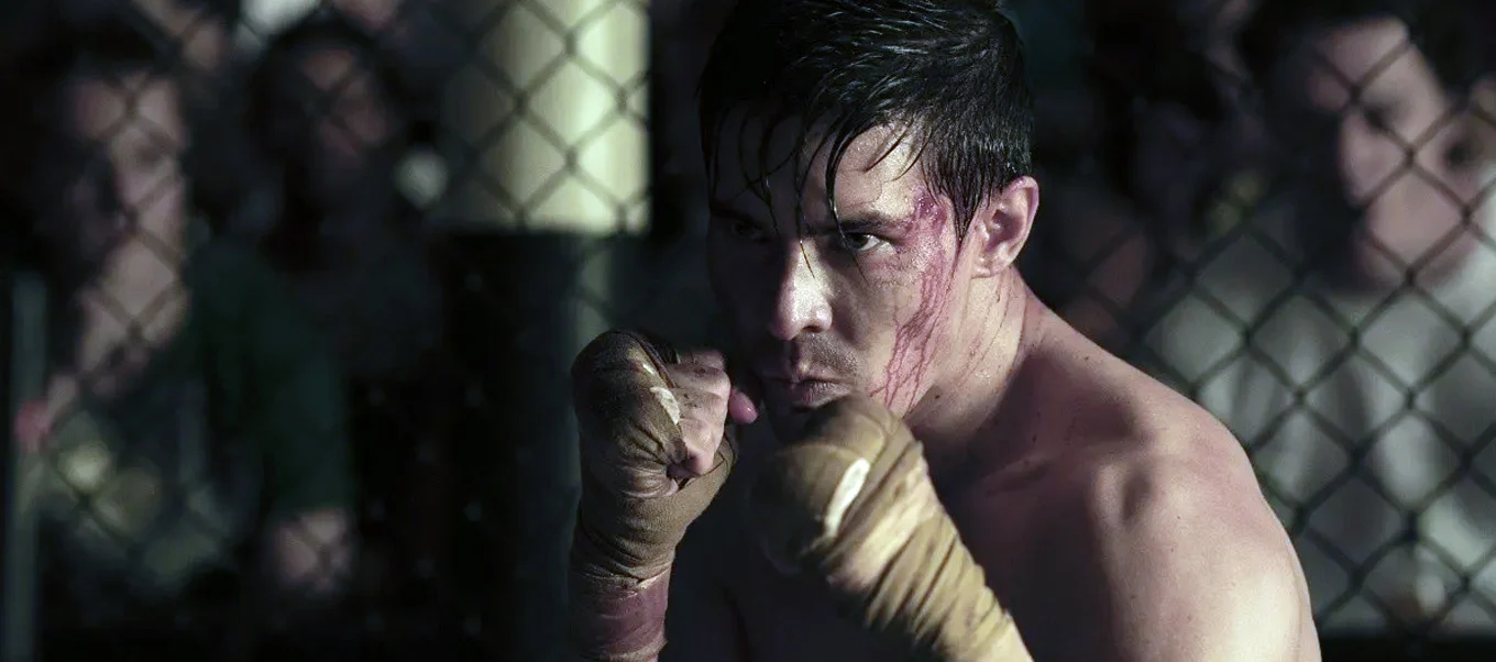 Cole Young, interpretado por Lewis Tan, ensangrentado en la jaula de MMA en la película de Mortal Kombat