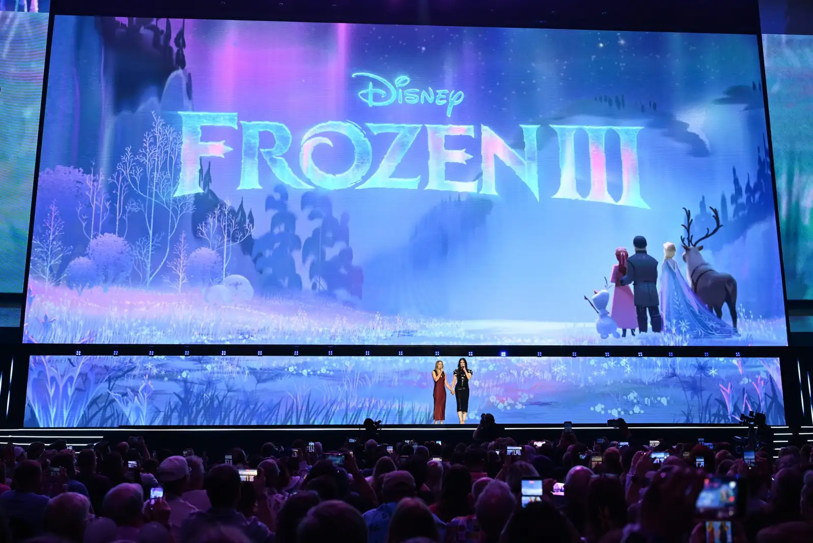 Primer vistazo a Frozen 3 proyectado en la pantalla del D23 2026, con Anna, Elsa, Kristoff, Olaf y Sven en un prado lila bajo auroras