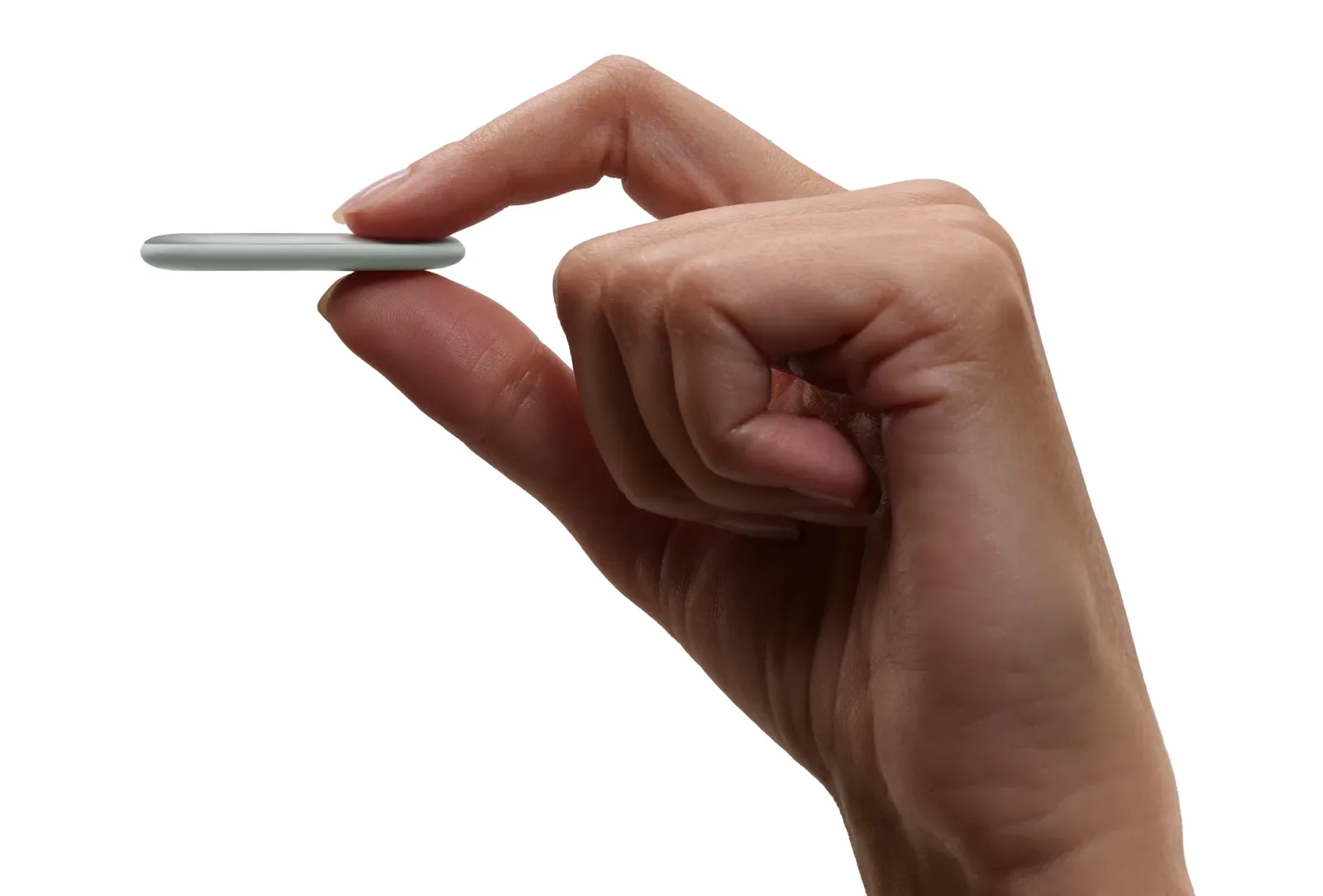 Una mano sostiene el Google Pixel Tag entre los dedos y deja ver lo fino que es el rastreador