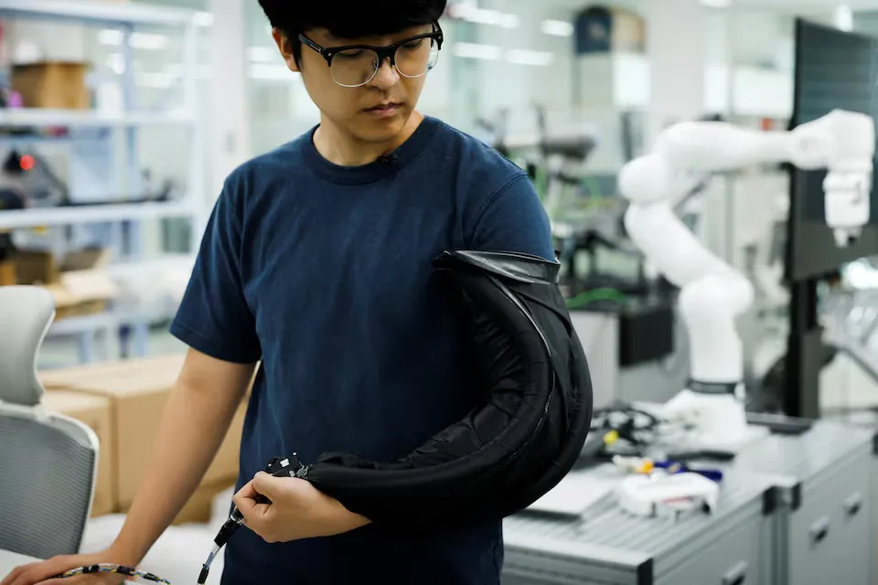 Un investigador de KAIST sostiene la prenda robótica enrollada en forma de aro antes de que se despliegue sobre el cuerpo