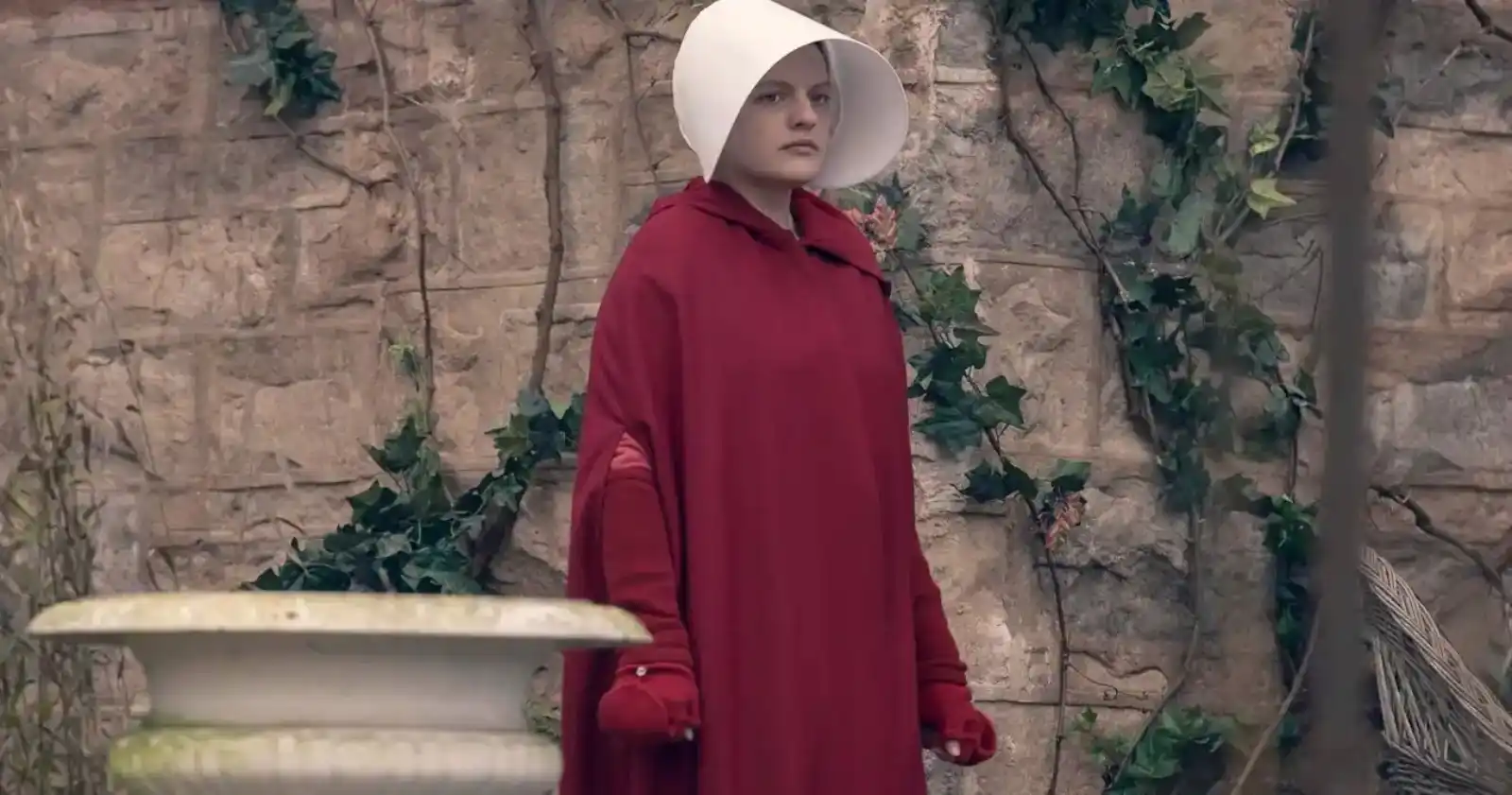 Una Criada con la capa roja y la cofia blanca de Gilead en The Handmaid's Tale, una de las mejores series distópicas