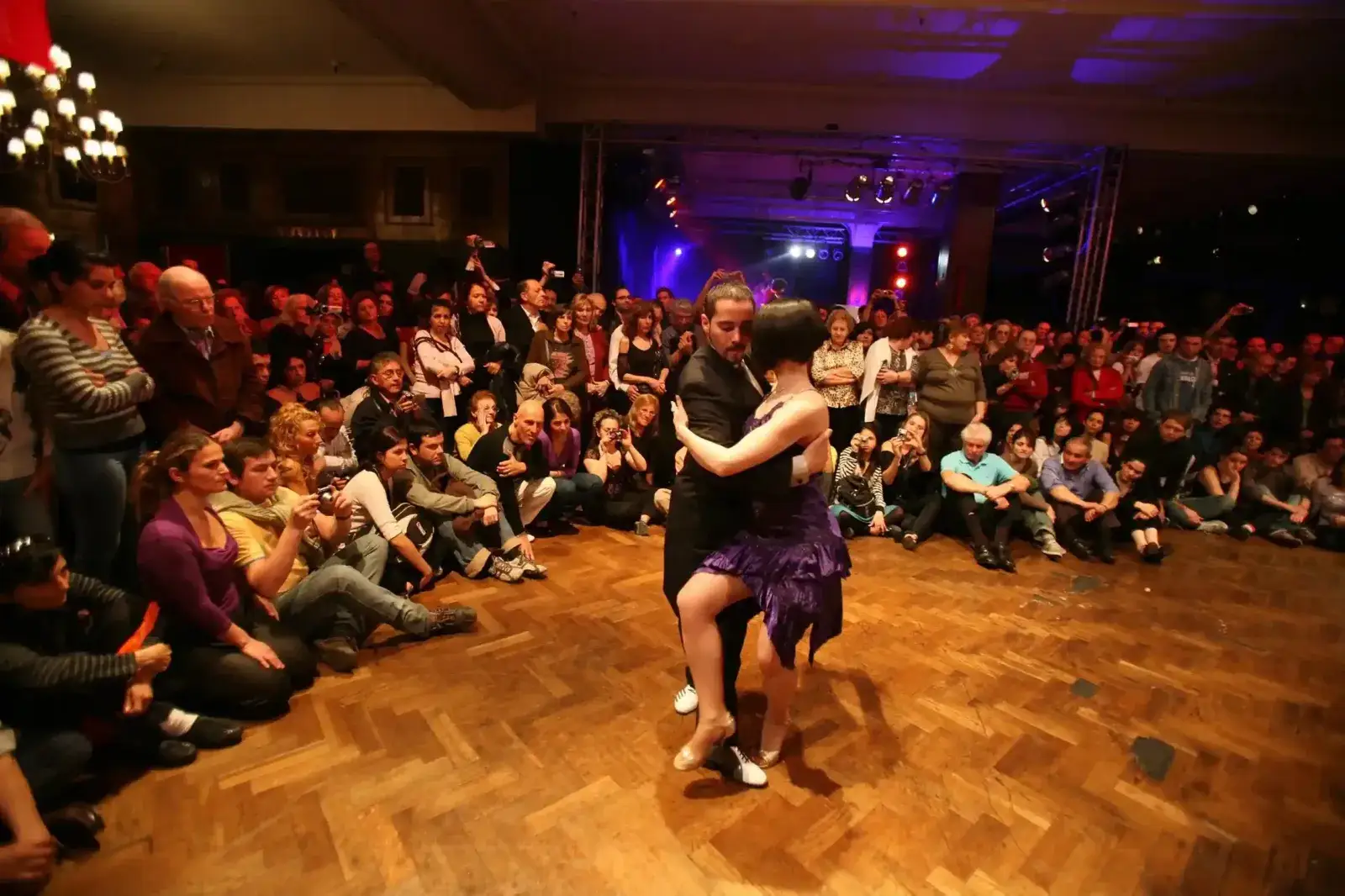 Pareja bailando tango rodeada de público en una milonga porteña, una de las escenas que retrata la colección de Google Arts & Culture