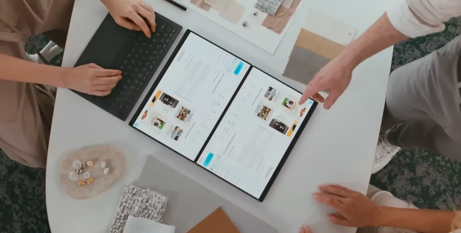 ASUS Zenbook DUO con las dos pantallas desplegadas sobre una mesa, compartida entre varias personas