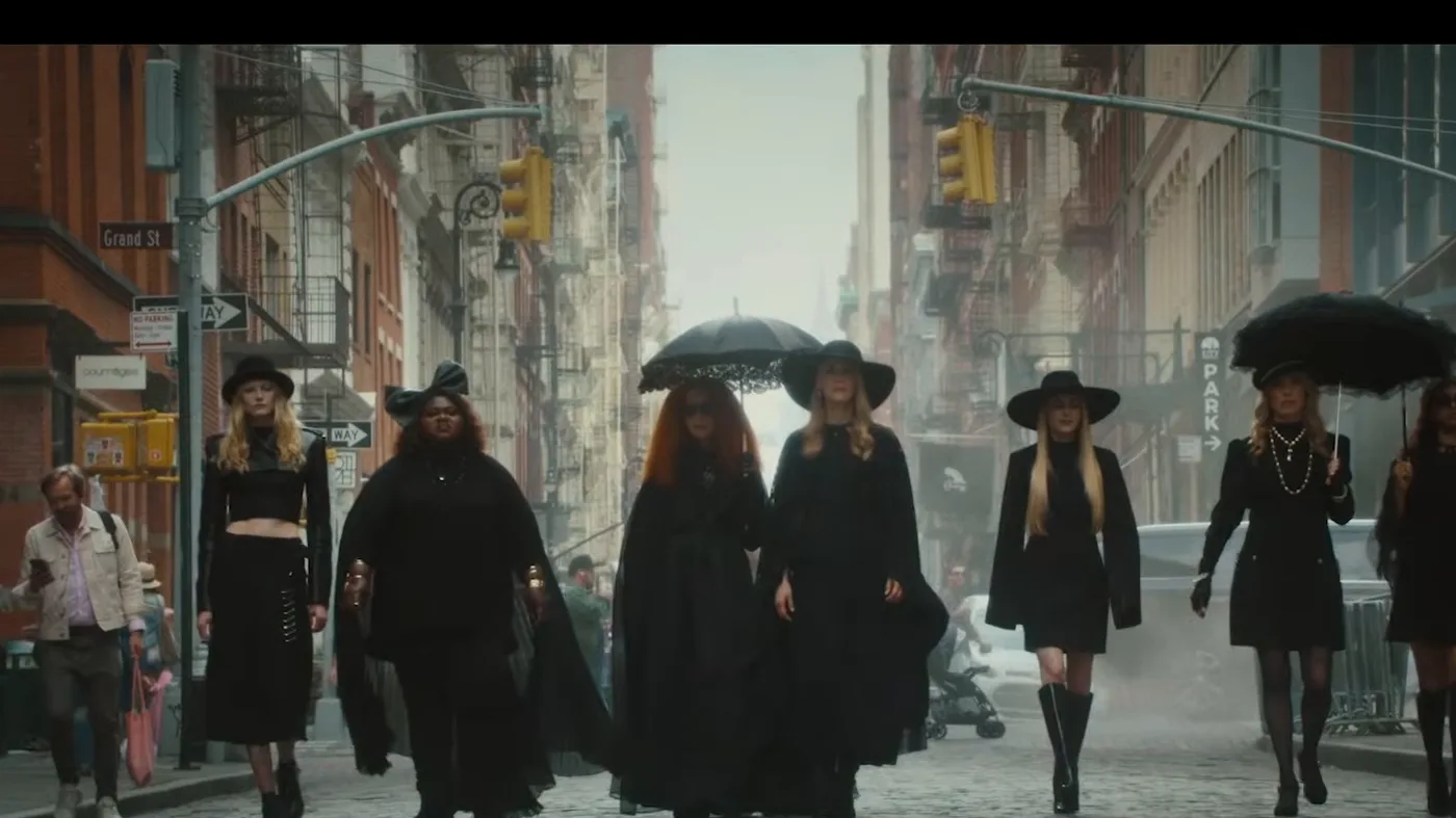 Un grupo de brujas vestidas de negro camina por una calle en el tráiler de American Horror Story 13
