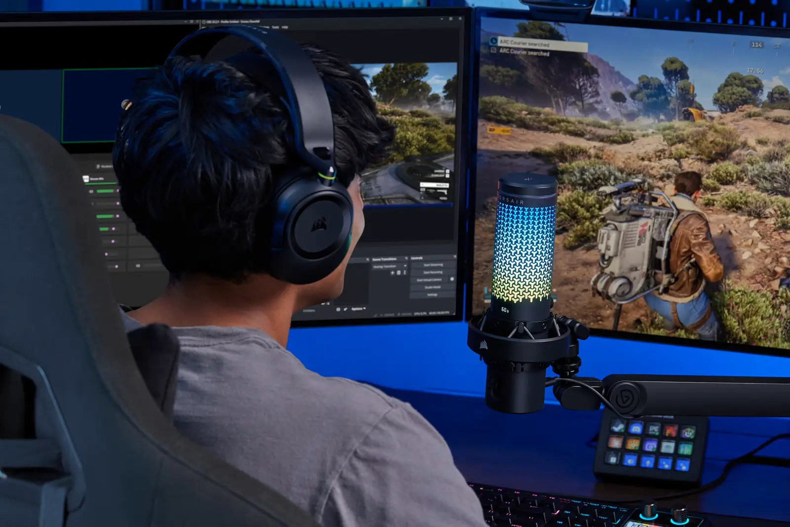 Un jugador con auriculares frente a dos monitores con el Corsair Voxara y un Stream Deck en el escritorio