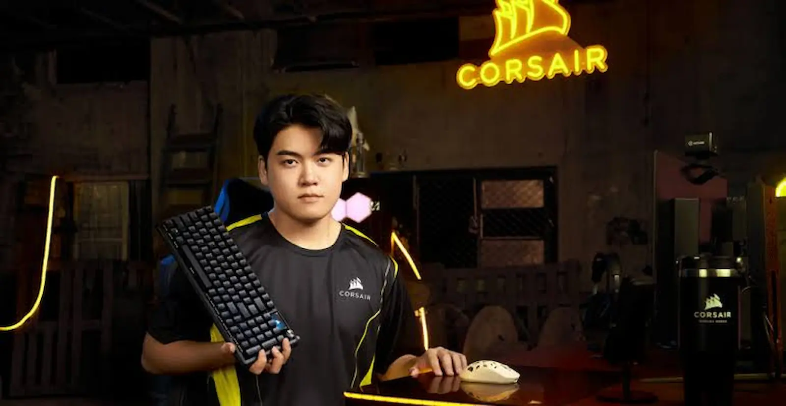Gumayusi sostiene el teclado Vanguard Pro 96 Gumayusi Edition frente a un cartel de neón de Corsair