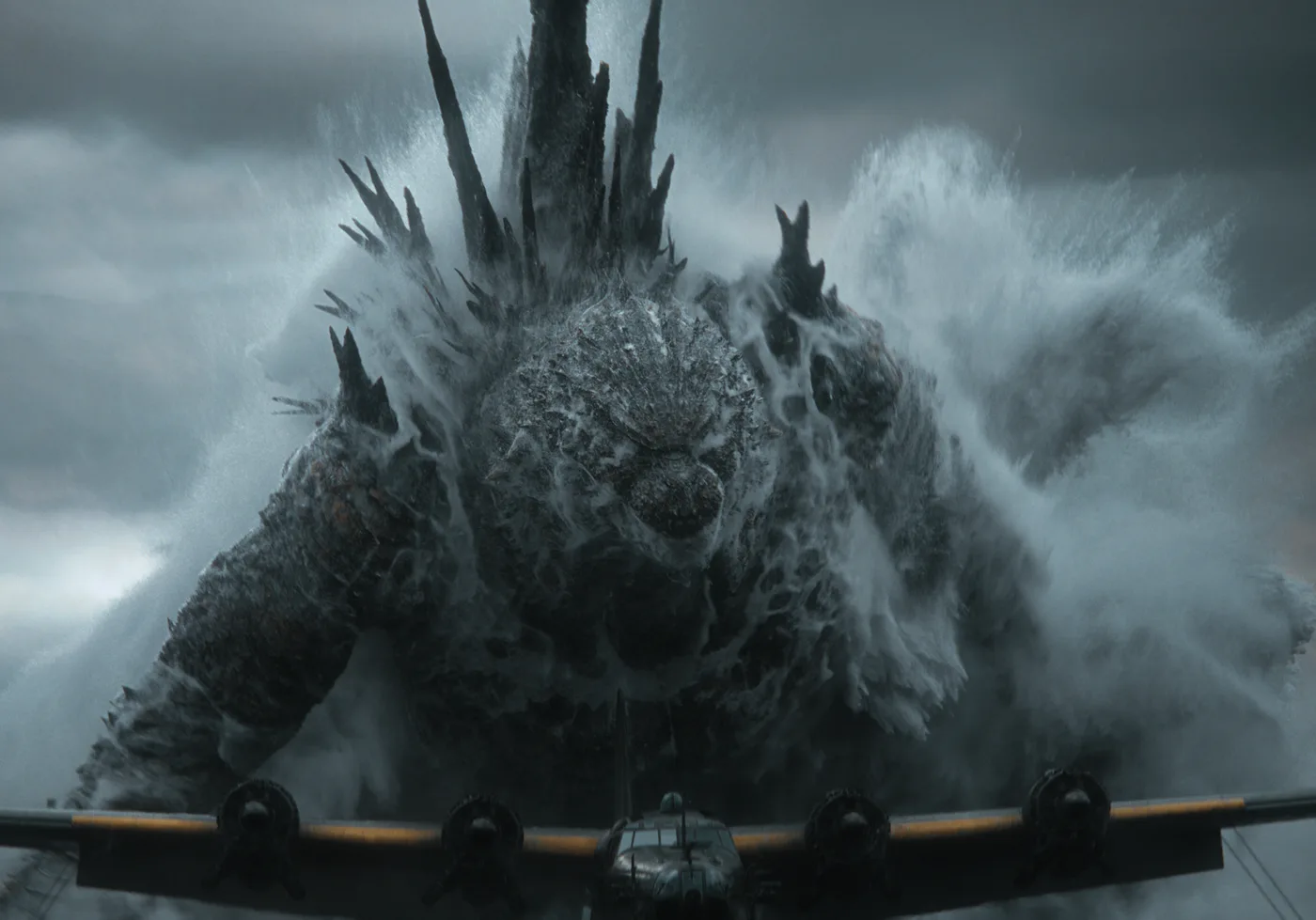 Godzilla emerge del mar frente a un avión de cuatro motores a hélice, en un plano filmado para IMAX