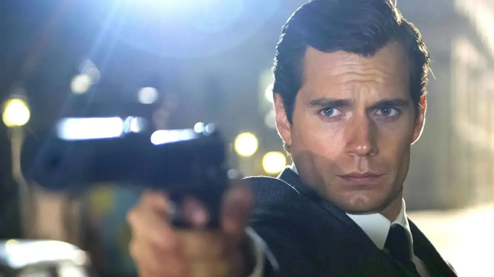 Henry Cavill de traje, apuntando con un arma