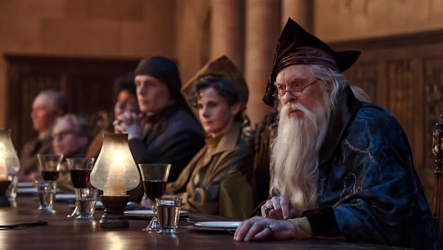John Lithgow como Albus Dumbledore en la mesa de profesores del Gran Comedor, en la serie de Harry Potter