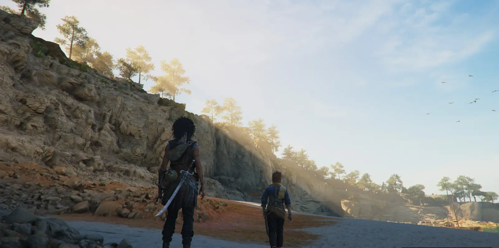 Sophia y un acompañante caminan por una playa al pie de unos acantilados