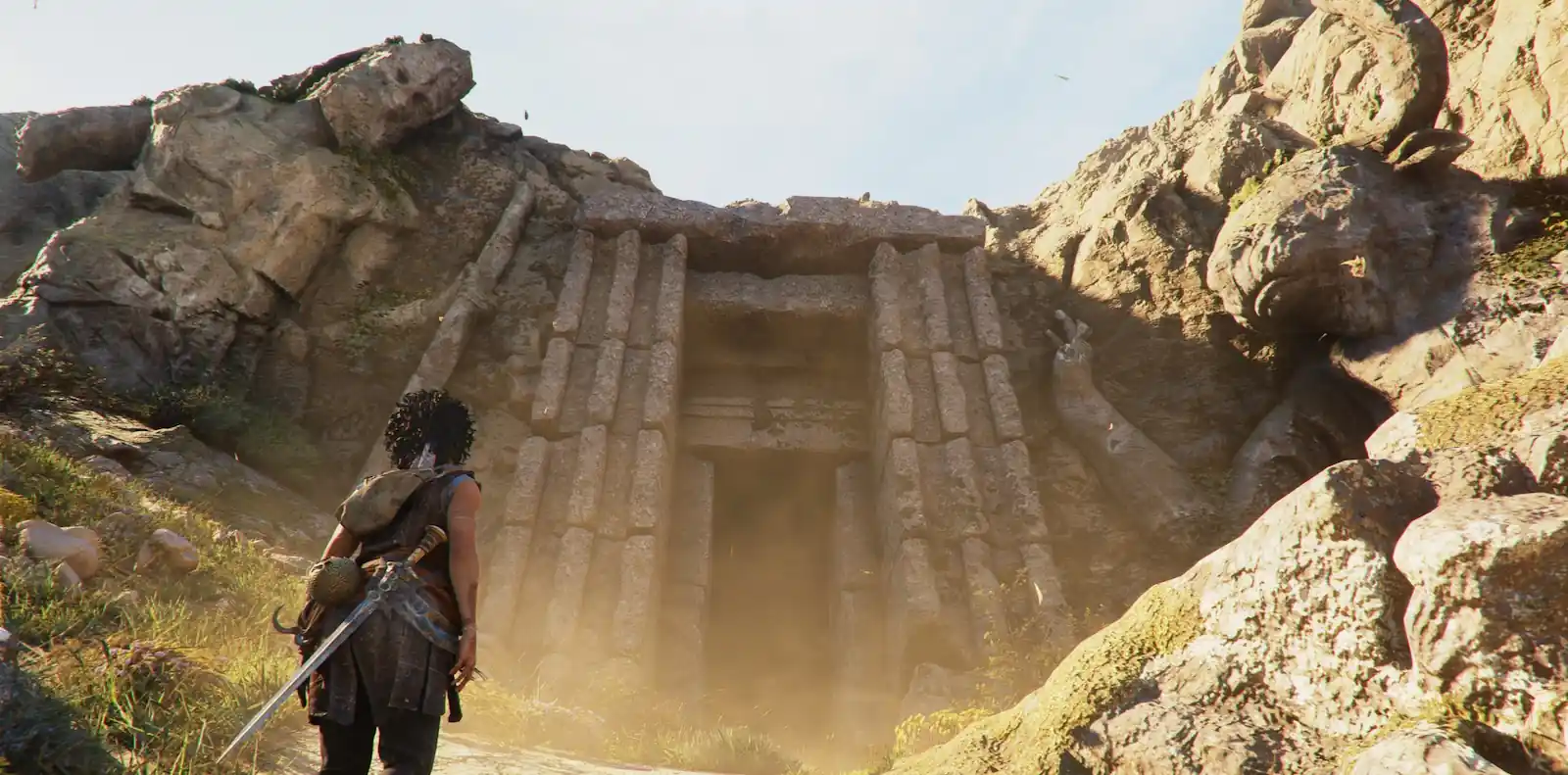 Sophia de espaldas, espada en mano, frente a la entrada de un templo tallado en la roca