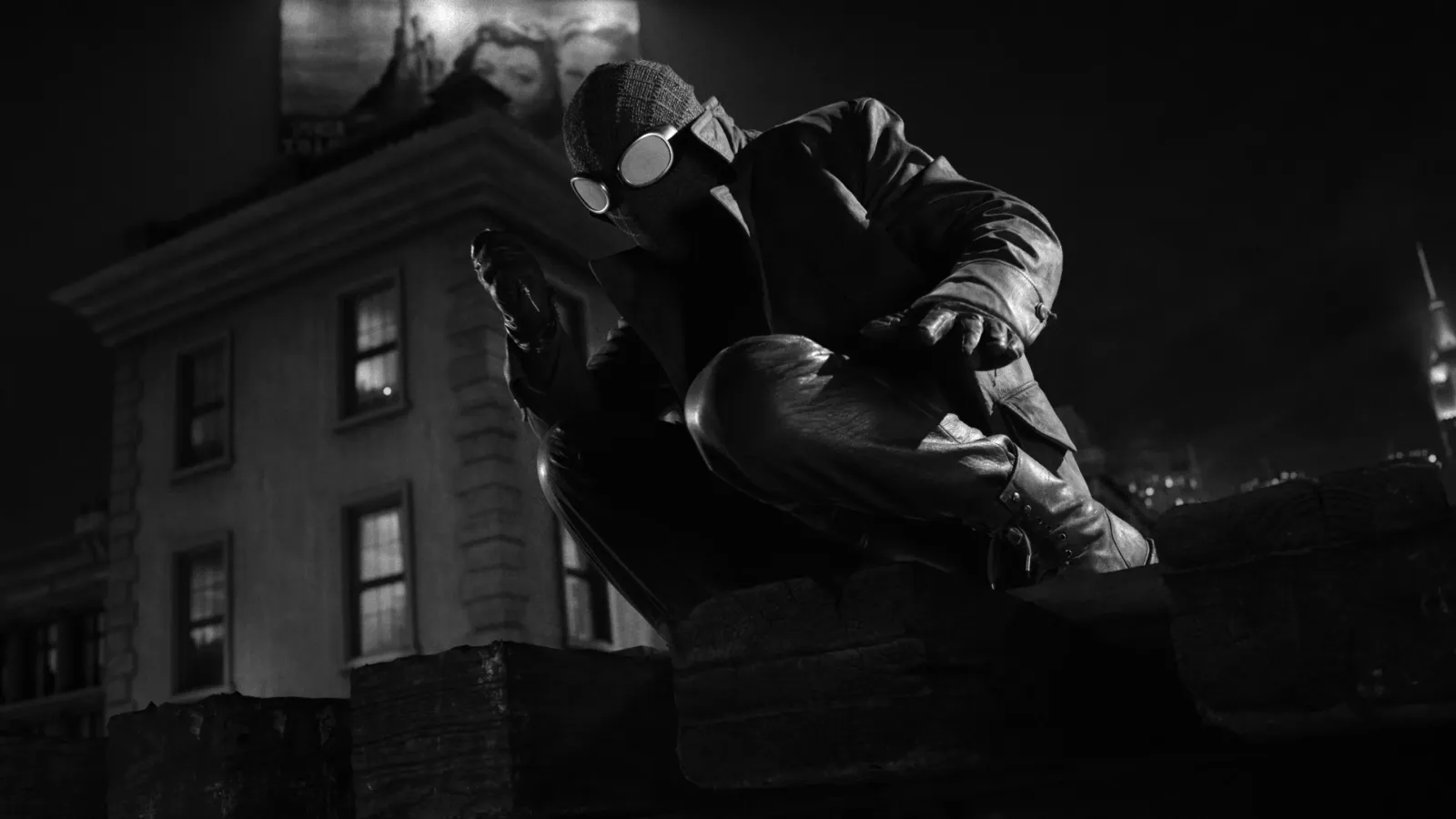 Spider-Noir agazapado sobre la cornisa de un tejado de noche, en blanco y negro