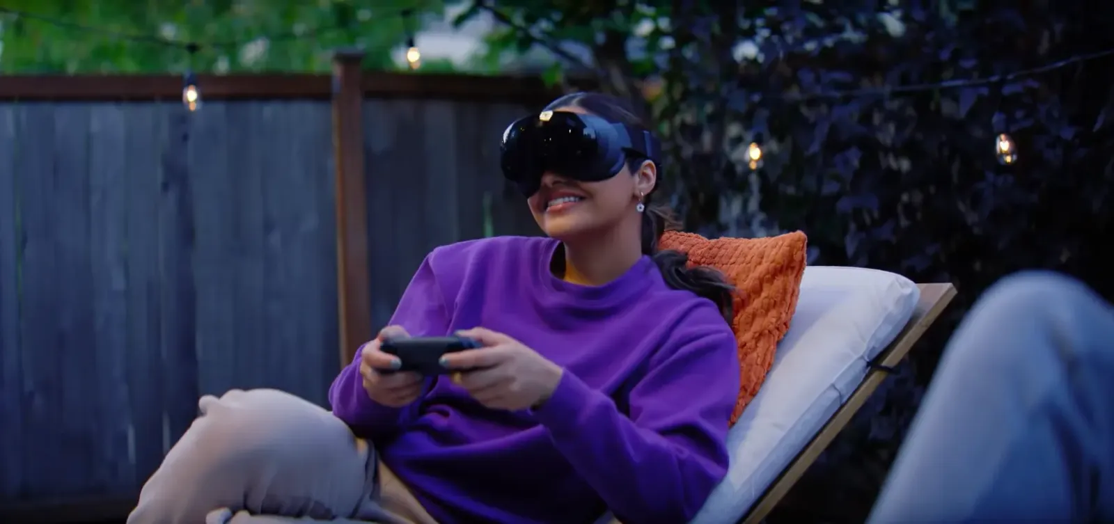 Una mujer juega con un control mientras usa Steam Frame en un jardín