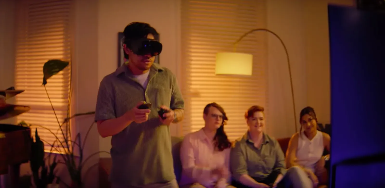 Un jugador usa Steam Frame en un living mientras otras personas lo miran desde el sillón