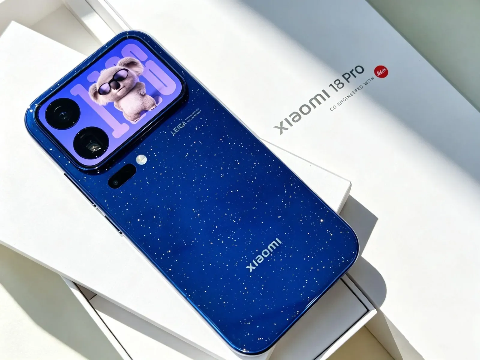 Xiaomi 18 Pro azul sobre su caja, con la pantalla trasera encendida