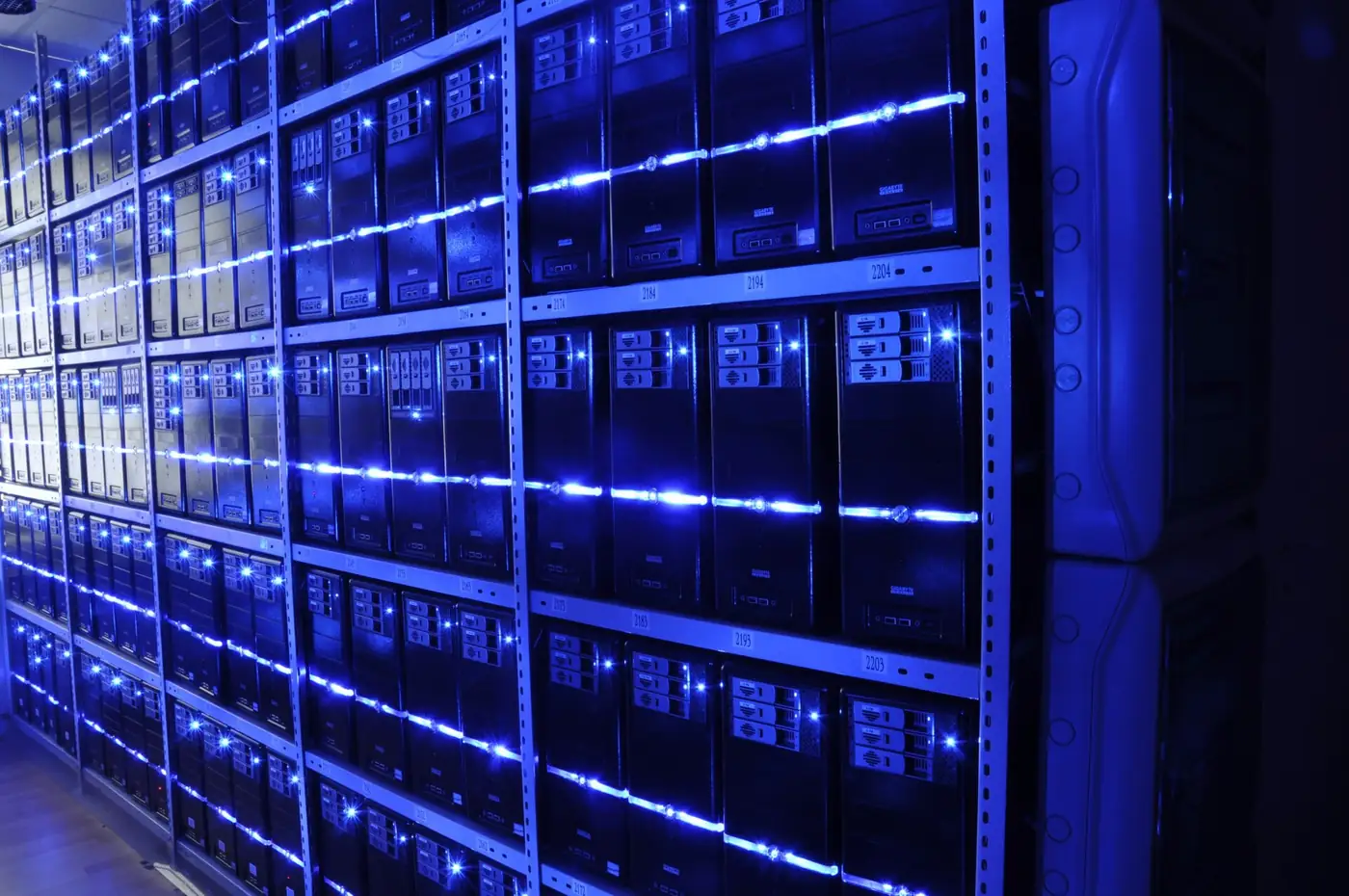 Pasillo de un centro de datos con racks de servidores iluminados por luces azules