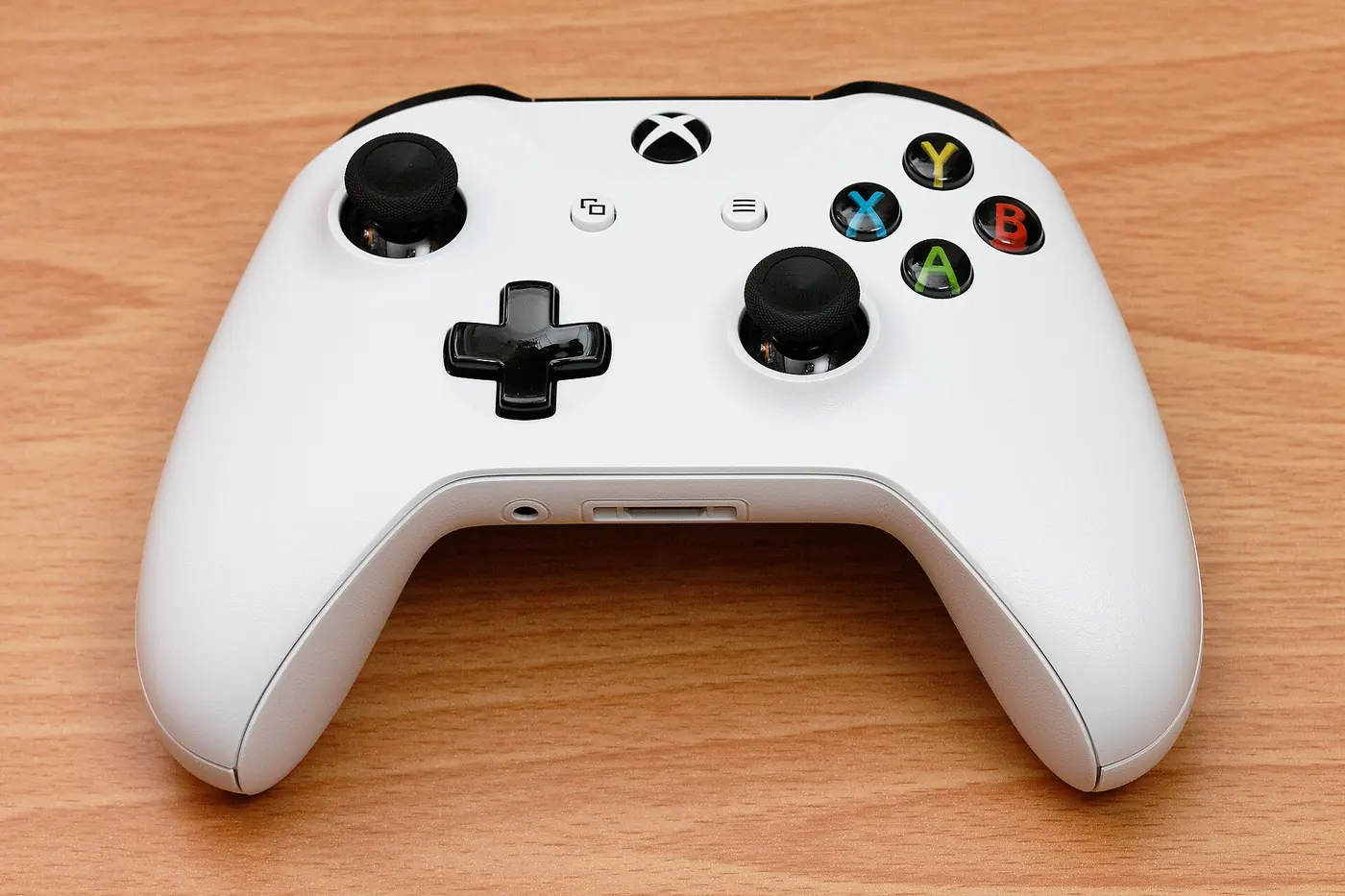 Control inalámbrico blanco de Xbox One apoyado sobre una mesa de madera