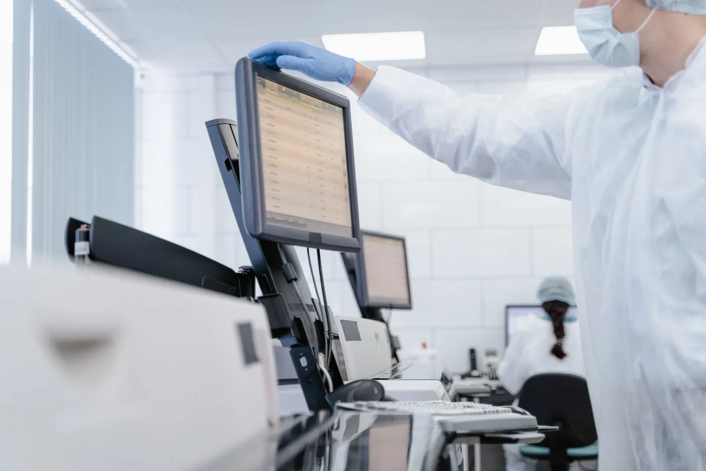 Investigador con equipo de protección analizando datos en la pantalla de un laboratorio