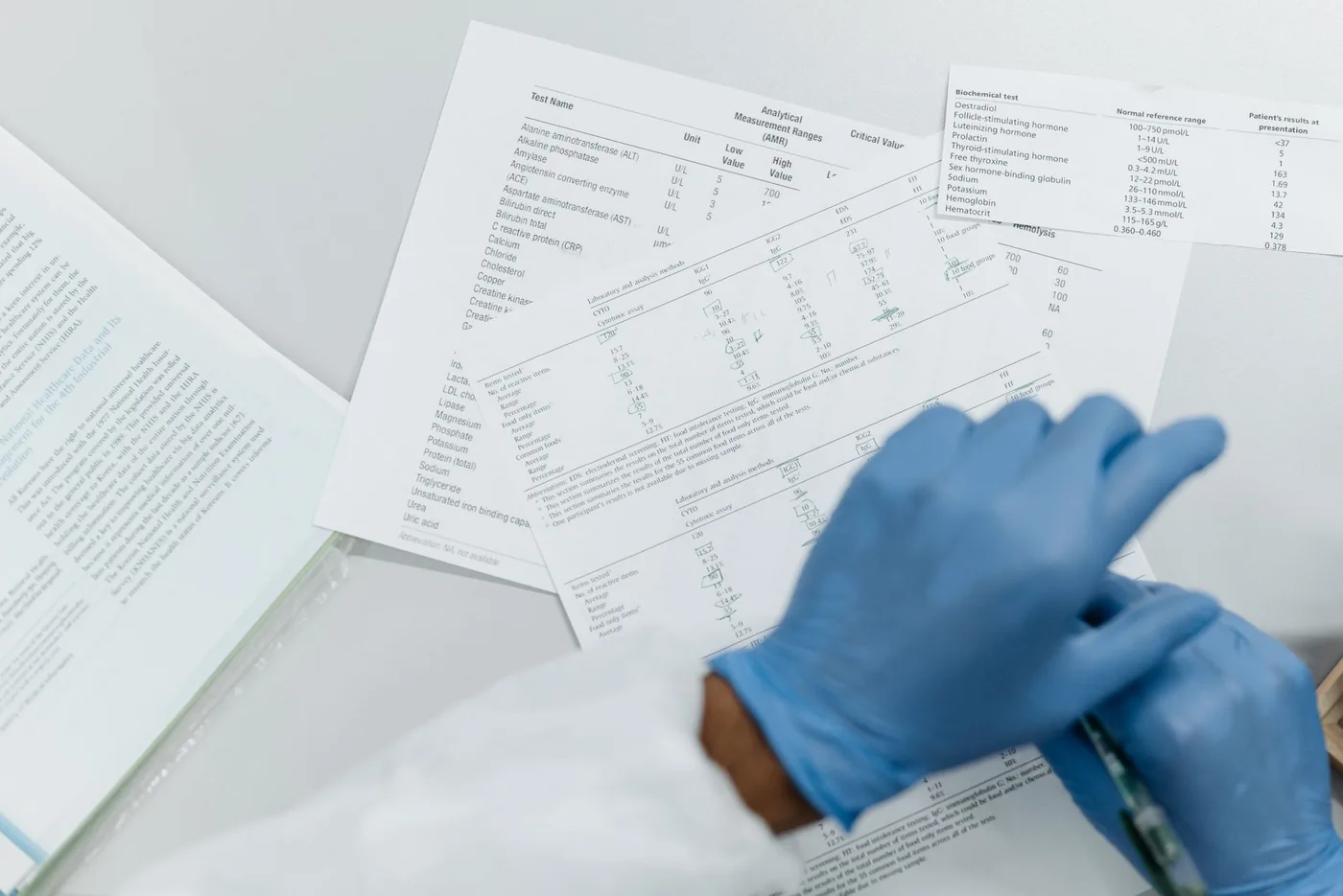 Manos con guantes de látex revisando resultados impresos de análisis de laboratorio