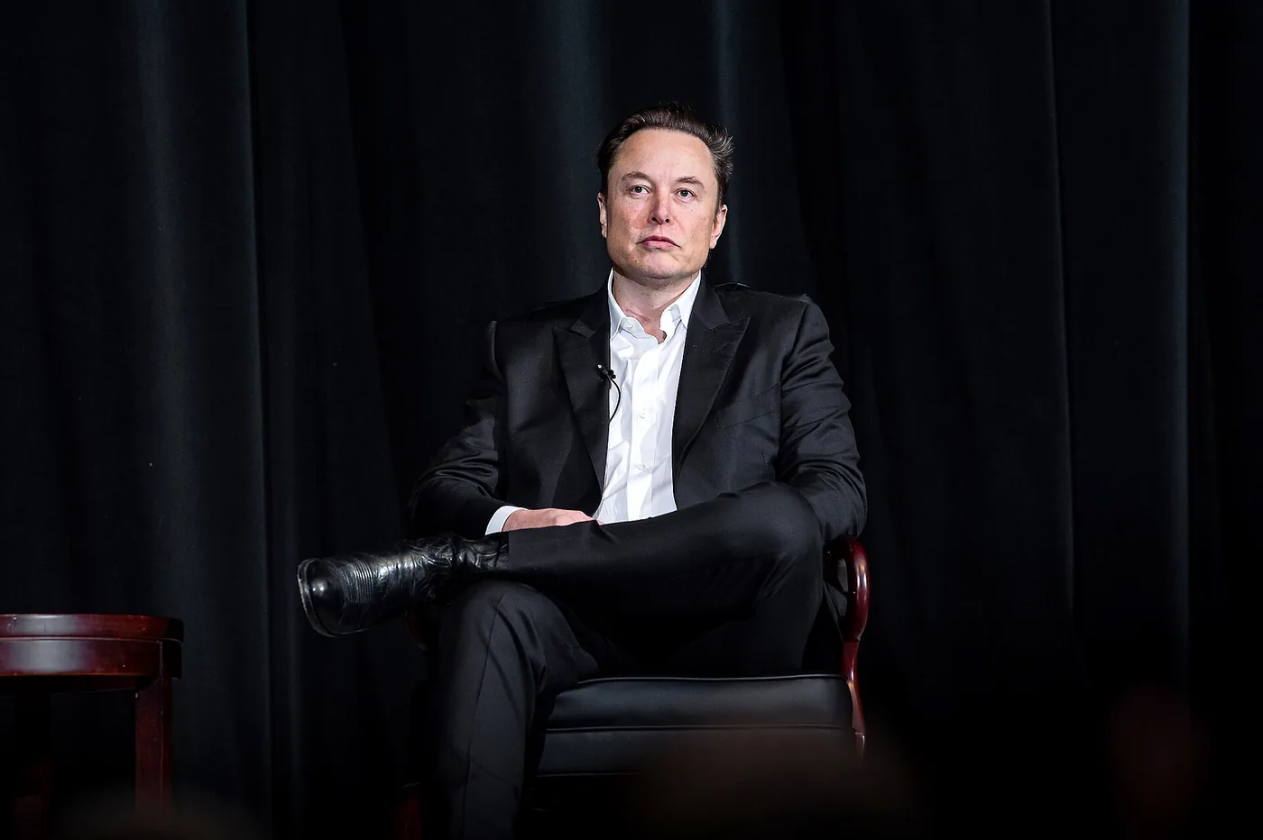 Elon Musk sentado de traje en un escenario con fondo oscuro, en Colorado en 2022