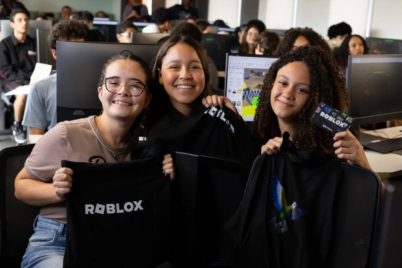 Tres chicas participantes de la Expedición Roblox en São Paulo muestran mochilas de Roblox