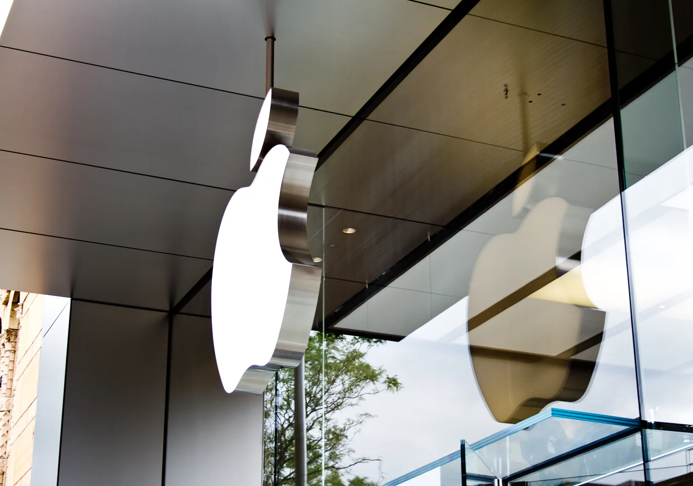 Dos logos de Apple colgados del vidrio en la fachada de una Apple Store