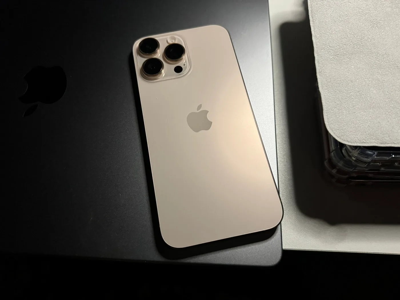 El módulo de cámaras trasero de un iPhone 16 Pro Max en color titanio, apoyado sobre un fondo oscuro