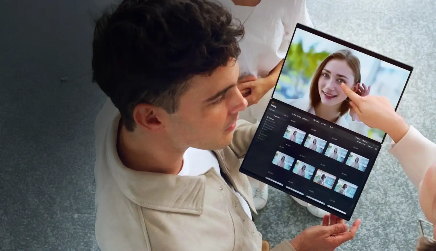 Un hombre sostiene la ASUS Zenbook DUO abierta mientras otra persona señala la pantalla superior